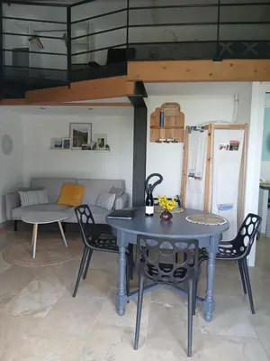 a table and chairs in a room with a couch at les cerisiers de stella in Blauvac