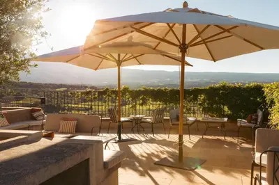 a patio with tables and chairs and an umbrella at Hotel Crillon le Brave in Crillon-le-Brave