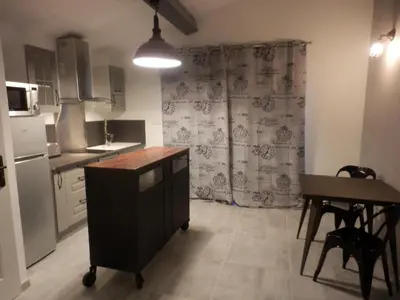 a kitchen with a sink and a table and a refrigerator at Suite luxe avec sauna et jacuzzi privée in Lambesc