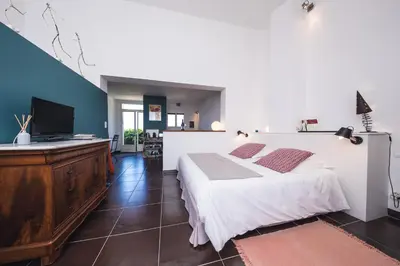 a bedroom with a large white bed and a flat screen tv at Le Mas de Plein Pagnier in Mazan