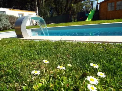 a fountain in the grass next to a swimming pool at Gîte de Léonie Moulin de Tartay en Avignon in Avignon