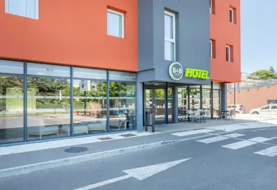 a store front of a hotel with tables and chairs at B&B HOTEL Aix en Provence Venelles in Venelles