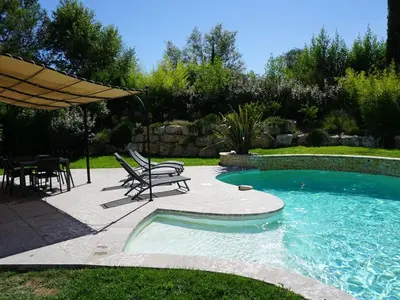 a swimming pool with a table and chairs and an umbrella at Golf de Pont Royal Villa du Lac climatisée 3 chambres Piscine chauffée Parking et Garage in Mallemort