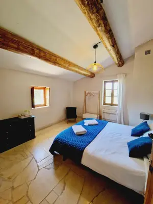 a bedroom with a large bed with blue sheets at Mas du Rollier Chambres d'hôtes in Eygalières