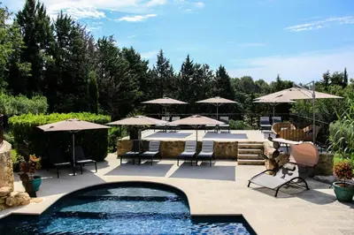 a patio with chairs and umbrellas and a pool at Le Mas de la Lombarde in Lourmarin