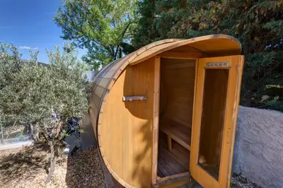 a wooden outhouse with a wooden door in a yard at Les Gargoulettes in Lauris