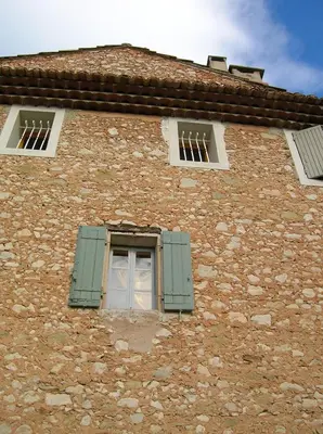 a brick building with a window with green shutters at Le Mas des Baux in Bédoin