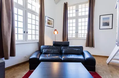 a living room with a leather couch and a table at Duplex 6 personnes, ascenseur, zone pietonne, 1 bis Rue Aude in Aix-en-Provence