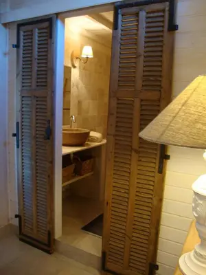 a bathroom with a sink and a wooden door at La Guéritaulde in La Tour-dʼAigues