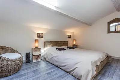 a bedroom with a bed and a wicker chair at Bastide de Fanny in Rognes
