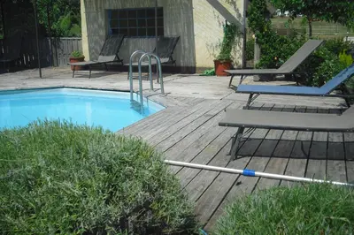 a swimming pool with a hose next to a wooden deck at Lou mas li Pitchoun 