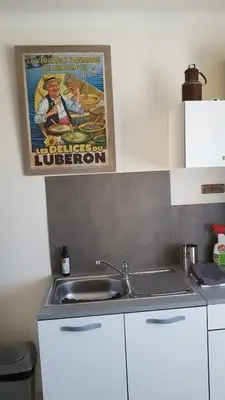 a kitchen with a sink and a poster on the wall at fleur de garance in Le Thor