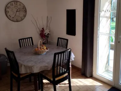 a dining room table with chairs and a clock on the wall at Le Moulin Des Ocres in Apt
