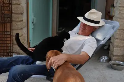 a man sitting in a chair with a cat and a dog at LA RESPELIDANE in Caromb