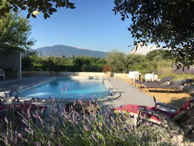 a swimming pool in a yard with mountains in the background at LA RESPELIDANE in Caromb