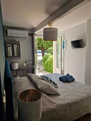 a bedroom with a bed with blue pillows on it at La Gourmandine in Saint-Andiol