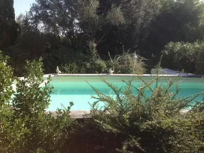 a blue swimming pool with trees in the background at Gite La Gourmandine in Saint-Andiol