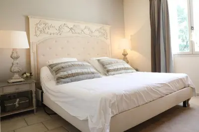 a bedroom with a white bed with two lamps and a window at Les Oursillons in Roussillon
