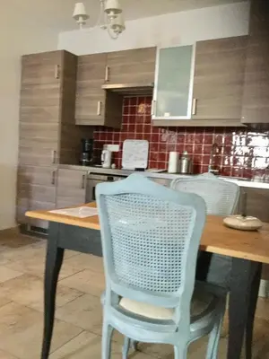 a kitchen with a wooden table and a blue chair at Un Coin De Luberon in LʼIsle-sur-la-Sorgue