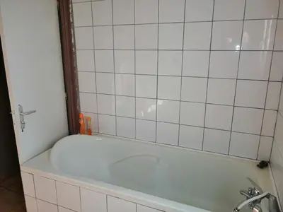 a bath tub in a bathroom with white tiles at Appartement proche du parc des expositions avignon in Avignon