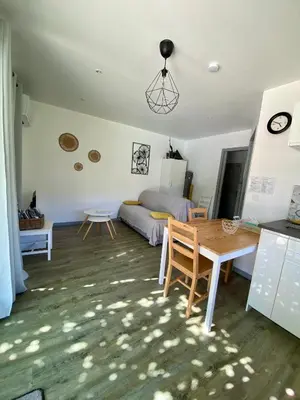 a living room with a table and a bed at La petite maison avec piscine face au Luberon in Robion en Luberon