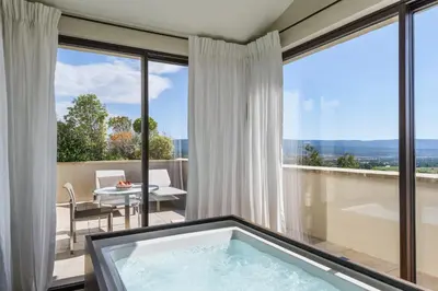a bathroom with a bath tub in front of windows at Coquillade Provence - Relais & Châteaux in Gargas
