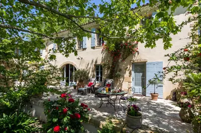 a patio of a house with a table and chairs at Gîtes Domaine des Machottes in Grans