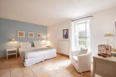 a bedroom with a bed and a chair and a window at Mas de Canfier in Robion en Luberon