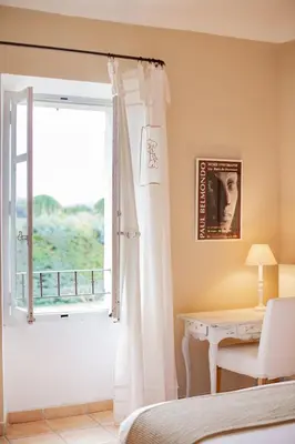 a bedroom with a window and a table and a bed at Mas de Canfier in Robion en Luberon