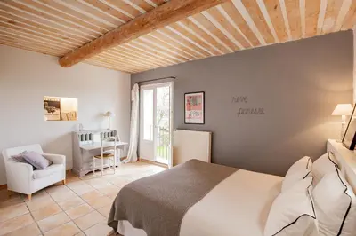 a bedroom with a bed and a chair in a room at Mas de Canfier in Robion en Luberon