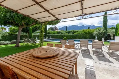 a wooden table and chairs under a large umbrella at Mas de Canfier in Robion en Luberon