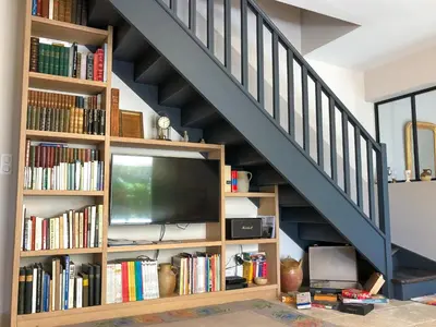 a book shelf under a staircase with a tv at le Gecko en Provence in La Roque-sur-Pernes