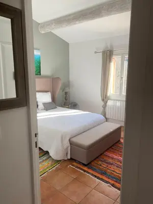 a white bedroom with a bed and a window at Villa des Roses in Roussillon
