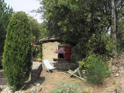 a stone house with a red door and two chairs at Chalet by Mont Ventoux with Stunning Views in Bédoin