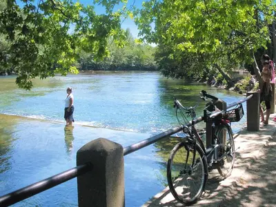 a man standing in the water near a river with a bike at Ménerbes Home with Private Pool in Ménerbes