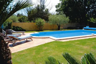 a swimming pool in a yard with two lounge chairs at Cozy Noves Home with Pool Access in Noves