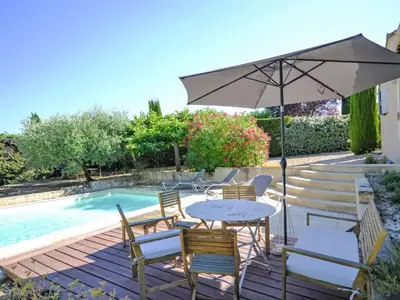 a table and chairs with an umbrella next to a pool at Holiday Home Les Iris by Interhome in Gargas