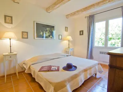 a bedroom with a bed with a hat and a book at Holiday Home L'Olivier by Interhome in Lagnes
