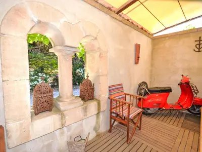 a red scooter parked on a patio with a house at Holiday Home L'Olivier by Interhome in Lagnes