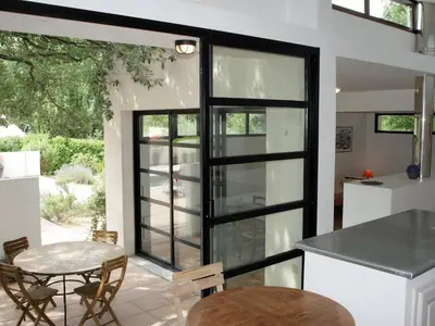 a kitchen with a glass door and a table at Holiday Home Villa Isabelle by Interhome in Gondonnets