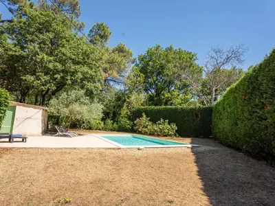 a swimming pool in a garden next to a hedge at Holiday Home Les Ecureuils by Interhome in Saint-Pantaléon