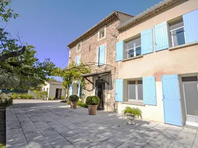 a large brick building with blue shutters on it at Holiday Home de la Roque by Interhome in Althen-des-Paluds