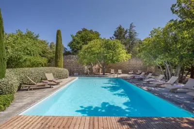 a swimming pool with chaises and chairs in a yard at Le Jas de Gordes in Gordes