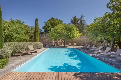 a swimming pool with chaises and chairs in a yard at Le Jas de Gordes in Gordes