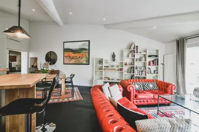 a living room with a red couch and a table at Escapade en Provence in LʼIsle-sur-la-Sorgue