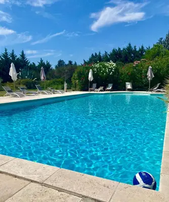 a blue swimming pool with chairs and a soccer ball at Gîte Crillon - Mas Les Fleurs d'Hilaire in Monteux
