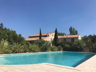 a swimming pool in front of a house at Gîte Crillon - Mas Les Fleurs d'Hilaire in Monteux
