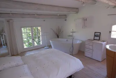 a bedroom with a tub and a bed and a sink at La Ferme in Saint-Marc-Jaumegarde