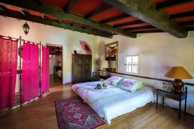 a bedroom with a large bed with pink curtains at La Ferme in Saint-Marc-Jaumegarde