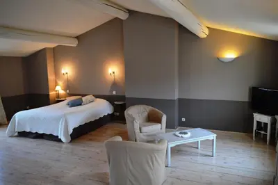 a hotel room with a bed and a table and chairs at Le Couvent in Apt